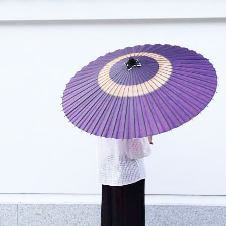 紫色の蛇の目傘をさす女性