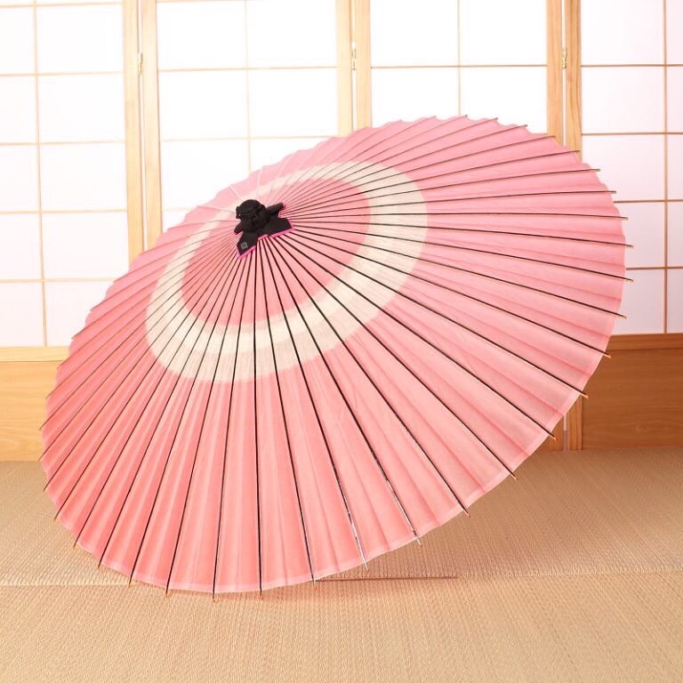ピンクの蛇の目柄の和傘を作っている様子